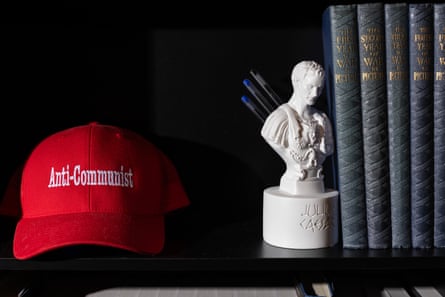 A red cap that says ‘anti-communist’ and a Julius Caesar pen holder on a shelf