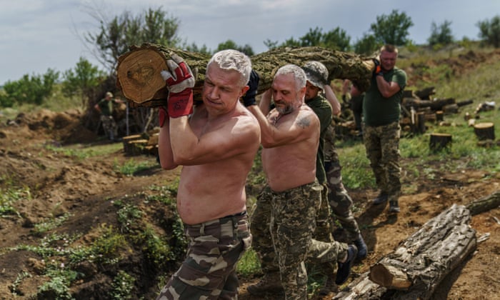 Members of the Dnipro-1 regiment carry logs to fortify their position near Sloviansk, Donetsk region