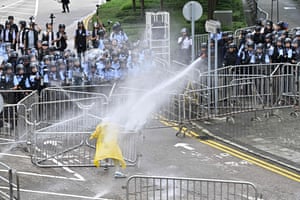 Police officers use a water canon on a lone protestor near the government headquarters in Hong Kong on June 12, 2019.