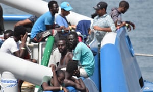 People wait on the deck of a Swedish navy ship as they wait to disembark in the Sicilian port of Catania after being rescued.