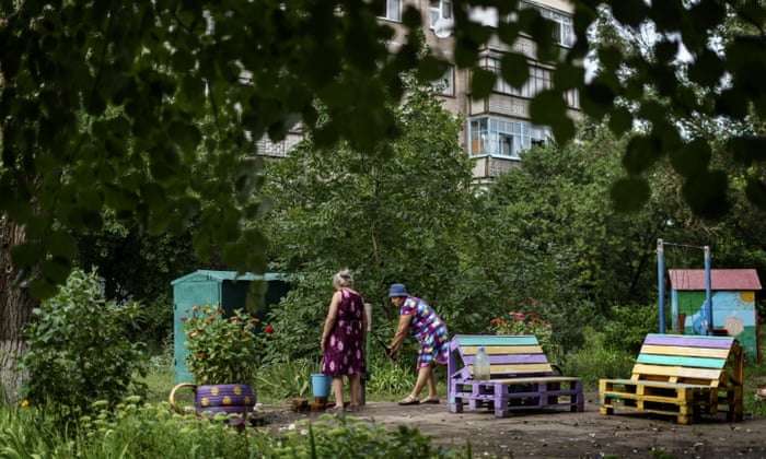 Two women pump water out of a well in the courtyard of an apartment complex in Sloviansk, Donetsk region, eastern Ukraine, Friday, Aug. 5, 2022. The city has no running water as artillery and missile strikes have downed power lines and punched through water pipes, leaving many in the area without electricity or water. (AP Photo/David Goldman)