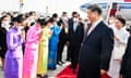 Thai women in colourful dresses bow to Xi and his wife as they walk down red carpet at airport