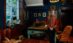 Mark Hinchliffe wearing a military jacket in the ‘gentlemen’s club room’ with dark blue walls