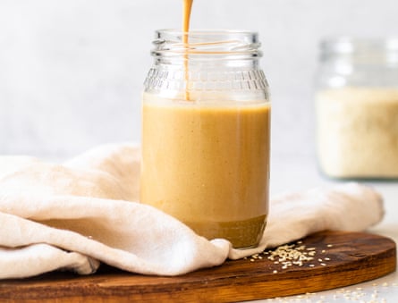 woman lifting spoon of tahini out of jar