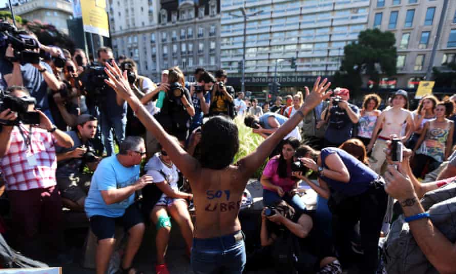 A woman poses topless with the words ‘I am free’ written on her back.