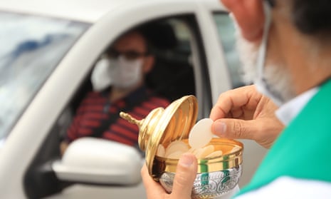A priest offers communion to a Catholic devotee during a drive-in mass celebrated in a parking lot due to the pandemic, in Bogota. A decree issued by the Colombian government on March 22 extended the prohibition of celebrating religious gatherings across the country until August 31.