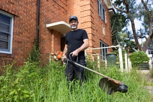 Man with lawnmower in front of brick building