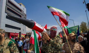 Men carrying mock missiles and an Iranian flag