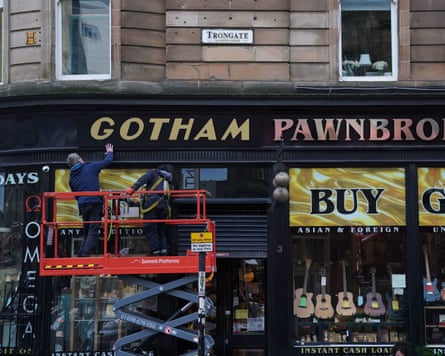 Set dressers transforming a street in Glasgow into Gotham City for the Batgirl film shoot.