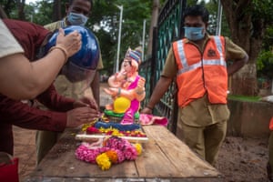 Devotees pay tribute, remove ornaments and pray to the statue of Lord Ganesh before it is taken by workers to be immersed in the artificial pond.