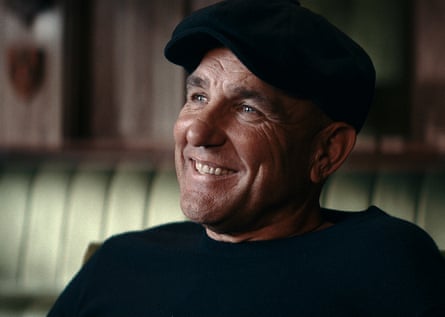 A man smiling wearing a flat cap and a black jumper