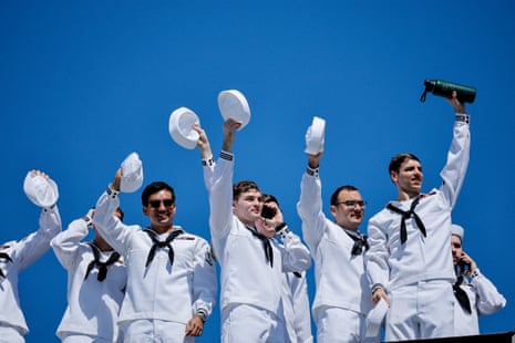 US Navy sailors wave their caps joyfully as their aircraft carrier returns home