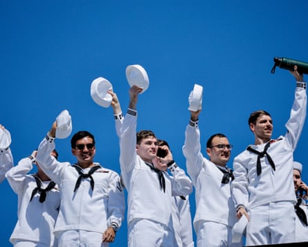 Uniformed sailors wave from the USS Abraham Lincoln.