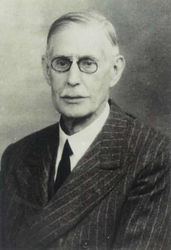Black and white formal photograph of Jules Strauss in a suit with black-rimmed glasses