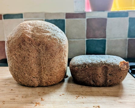 Two homemade loaves of bread, one tall and one flat, sit on a wooden board