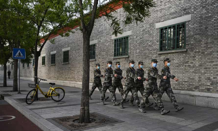Chinese soldiers wear protective face masks as they march along a street in Beijing.