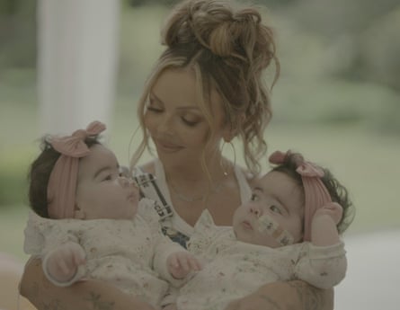 She looks adoringly at one of her two babies as she holds them in her arms