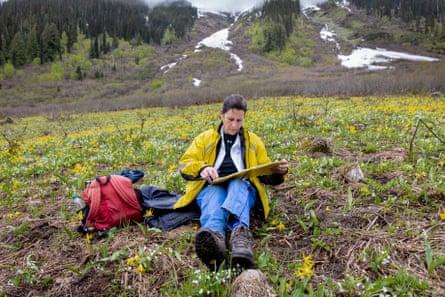 Lana Ciarniello looks at a book sat down at the side of a mountain