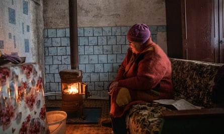 Kateryna Sliusarchuk, 71, keeps warm by her stove