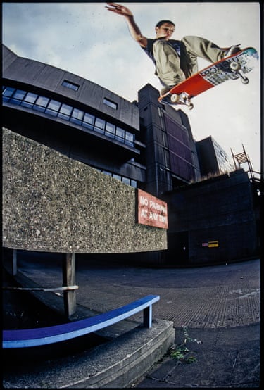 A person jumping high on a stakeboard, with a building in the background