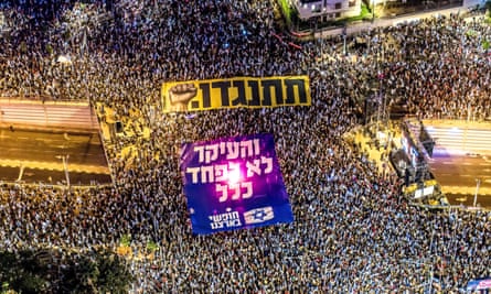 Protesters holding banners with the words ‘resist’ and ‘the main thing is not to be afraid at all’ in Hebrew