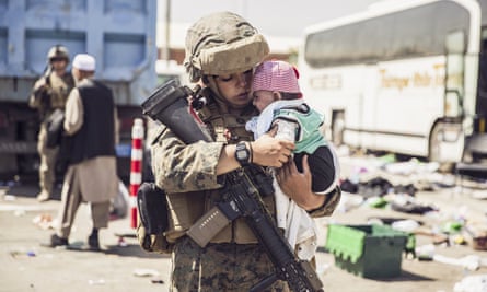 A Marine with the 24th Marine Expeditionary Unit carries a baby as the family processes through the evacuation control center in Kabul.