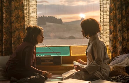 Mia Tharia and Jenna Ortega sit talking near a sunset-lit window in Klara and the Sun