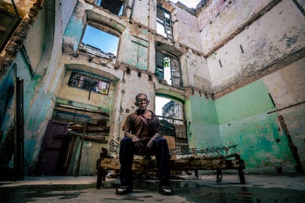 Jesus, 78, sits on the remains of a bed at 62 Cuba Street, where lived before it collapsed
