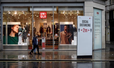 A women walks past a shop with a social distancing sign outside it on Oxford Street in London