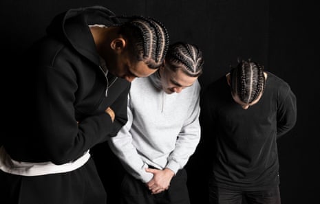 Three men with braided hair look downwards