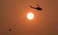 A water-bombing helicopter is seen flying past the sun during bushfires in Queensland in November 2023