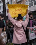 A woman, seen from behind, holds a protest banner aloft