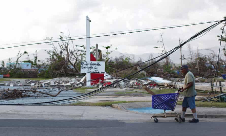 A man pushes a shopping cart past downed cables in Puerto Rico. Trump faced criticism that his administration was initially slow to aid the island.