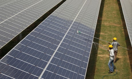 Workers clean photovoltaic panels inside a solar power plant in Gujarat, India