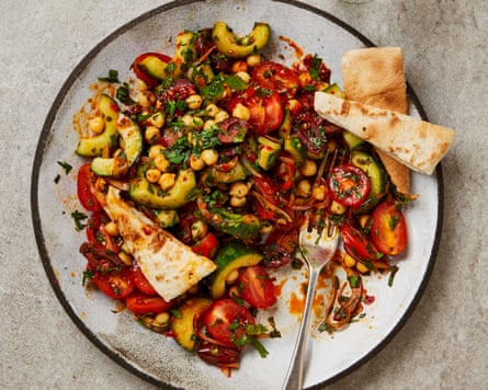 A plate of no-cook tomato and chickpea salad with pita bread wedges and a fork