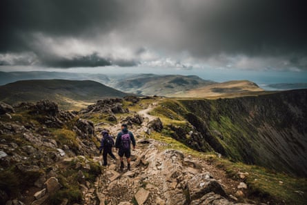 Hikers on a Welsh mountain top underneath grey skies.