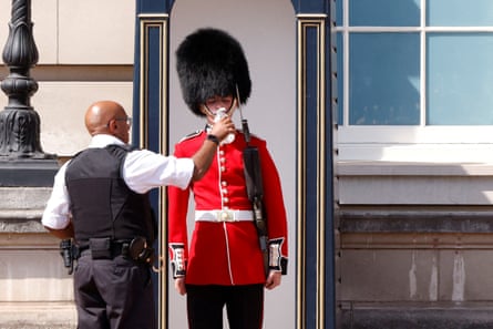 A man holds up a water bottle to give a member of the Queen’s Guard a drink during the 2022 heatwave in London