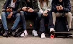 Young people sitting in a row looking at their phones