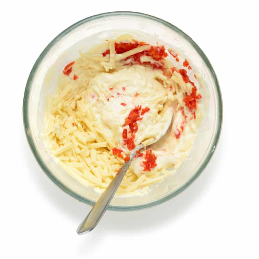 Mezcle la mayonesa con la mostaza, luego agregue todo menos un puñado de queso y los pimientos, si los usa, y sazone al gusto.