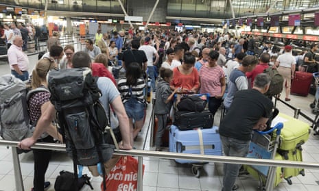 Passengers queue to check in at Schiphol airport in July.
