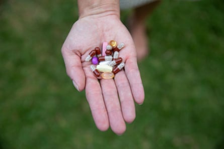 A woman’s hand holding a palmful of birghtly coloured pills