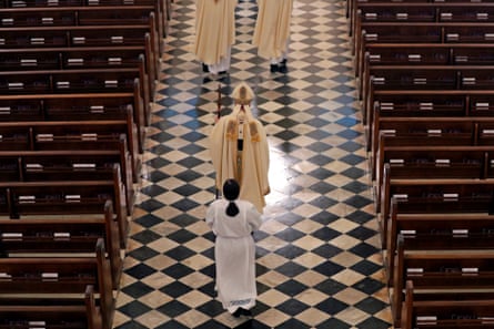 An archbishop walks between church pews.