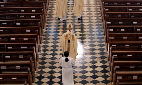 Person wearing religious clothes stands in church aisle