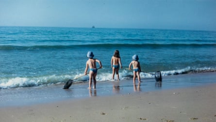 Fiona Collier, who lost her parents and sister in a helicopter crash, on a beach in Portugal, as a girl, in 1967, with two sisters, in bikini bottoms, holding fishing nets