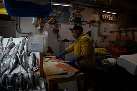 A man wearing gloves prepares fillets in a fish shop