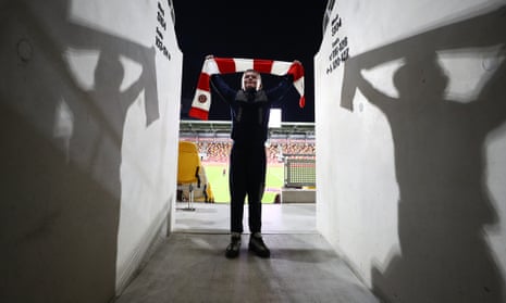 A Brentford fan holds up a scarf inside the Brentford Community Stadium prior to the Premier League against Brighton & Hove Albion.