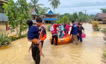 Rescuers carry people affected by a flood in Wajo, South Sulawesi, Indonesia