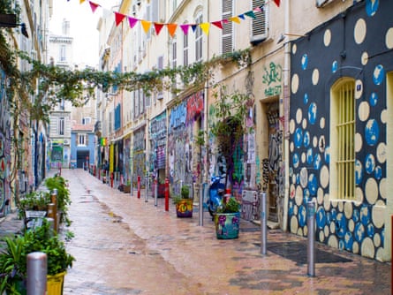 A small, tiled street with graffiti and plants.