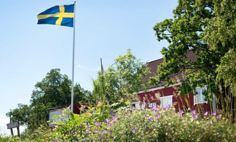Summer house in Sweden amid a garden in bloom. The house flies the Swedish flag.