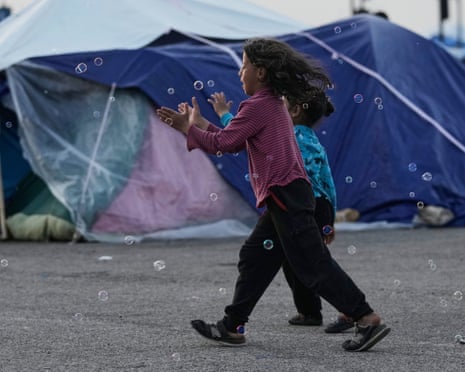 Girls chase bubbles next to their family’s tents used as shelter after fleeing Israeli bombardment in Beirut’s southern suburbs